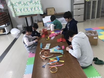 花紙で作る花のつくり方を子どもたちに教える学生たち